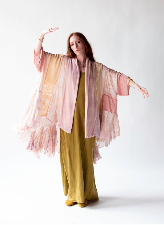 Woman wearing a long, light-colored kimono-style garment over a green dress on a white background